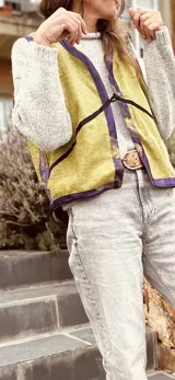 Chaleco color crema con ribete amarillo, de corte recto y sin mangas.