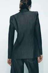 Blazer gris oscuro con cuello solapa, manga larga, bolsillos con solapa en el delantero y cierre frontal con dos botones forrados.