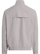 Campera Calvin Klein color gris claro, confeccionada en nailon arrugado reciclado, con cuello alto, puños y bajo elásticos, cierre frontal con cremallera, bolsillos laterales con cremallera, abertura de ventilación en la espalda, forro de poliéster reciclado e insignia con el logo de goma en la manga.