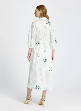 Vestido camisero midi blanco con estampado floral, cuello camisero, mangas 3/4 abullonadas, cierre frontal con botones y lazo ajustable en la cintura.
