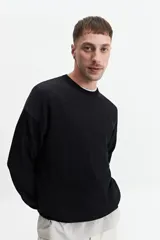 Buzo de punto color crudo, de corte oversize, con cuello redondo y puños.