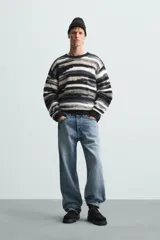 Sweater de punto con cuello redondo y manga larga, con diseño de rayas horizontales en tonos negro, gris y blanco.