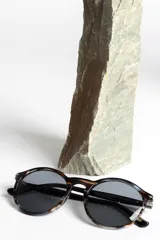 Lentes de sol unisex con montura redonda de carey y lentes polarizadas grises.