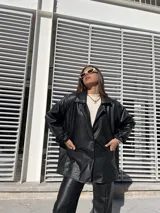 Blazer oversize de ecocuero color negro, con mangas largas con botón (tipo camisa) y bolsillos amplios delanteros.