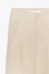 Pantalón marrón de lino, de tiro alto, con bolsillos delanteros y traseros.