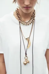 Set de tres collares de diferentes largos: gargantilla de anillas metálicas, collar largo de cuerda con charms metálicos y collar de eslabones metálicos con colgante de cuerno de resina.