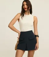 Short pollera de tiro alto color verde oliva, de corte sastrero con solapas delanteras simulando bolsillos y recorte en V en el ruedo.