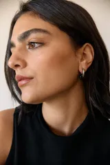 Aros de acero quirúrgico hipoalergénico con forma de argolla plateada y dije circular colgante de piedra natural color azul.