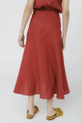 Falda midi color ladrillo, de corte evasé y tiro alto, con bolsillos laterales y botón decorativo en la cintura.