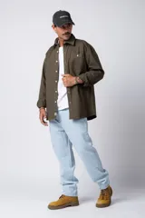 Camisa verde militar de manga larga, corte oversize, con cuello clásico, cierre frontal con botones y bolsillo en el pecho. Confeccionada en algodón suave y con costuras a la vista.