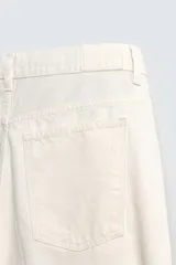 Bermuda de jean azul con lavado medio, corte holgado, cinco bolsillos, roturas y cierre frontal con cremallera y botón.