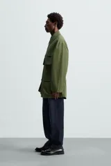 Parka verde militar de corte relaxed fit confeccionada en tejido técnico ligero. Cuello solapa y manga larga. Bolsillos de plastrón con solapa en delantero. Cintura ajustable en interior. Cierre frontal con cremallera oculta por solapa con botones a presión.