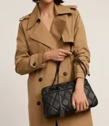 Bolso bandolera negro acolchado con patrón de rombos, asa de cadena y cierre de cremallera.