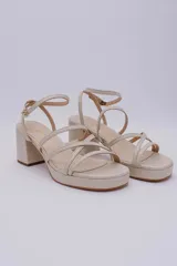 Sandalias de cuero color beige con plataforma y taco cuadrado. Tiras finas cruzadas sobre el empeine y tobillo con hebilla ajustable.