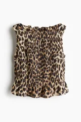 Top sin mangas con estampado animal print, corte ajustado, diseño punto smock, escote bote con volados y peplum.