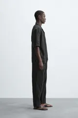 Pantalón negro de corte amplio, con textura acanalada, cintura elástica ajustable con cordón, bolsillos laterales y traseros de vivo.