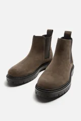 Bota Chelsea color marrón topo de cuero serraje, con elásticos laterales negros, tirador trasero y suela track.