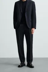 Pantalón de vestir azul marino, de corte recto, con bolsillos laterales y traseros. Se ajusta a la cintura con cinturón de cuero marrón.