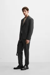 Blazer slim fit color gris oscuro confeccionado en tejido con viscosa. Tiene cuello con solapas de muesca, manga larga con puño abotonado, bolsillo de vivo en pecho, bolsillos de solapa en cadera, bolsillo interior, bajo con aberturas en espalda y cierre frontal con botones.