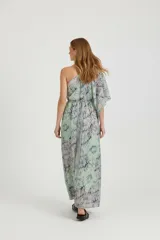 Vestido largo estampado, con diseño paisley en tonos azules y morados. Presenta un escote asimétrico con una manga corta abullonada en un hombro y el otro descubierto. La cintura es ajustada con elástico y la falda es suelta.