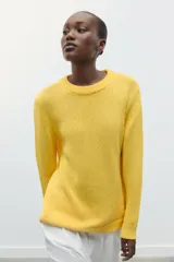 Jersey amarillo de punto rústico, corte recto, cuello redondo y manga larga con terminaciones en rib.