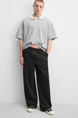 Pantalón jogger negro de corte ancho, confeccionado en tejido de algodón con interior de rizo. Cuenta con cintura elástica ajustable con cordón interior, bolsillos laterales y bolsillo trasero de parche.