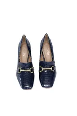 Zapato de cuero azul noche con estampado de cocodrilo, punta cuadrada, detalle metálico dorado y taco geométrico de madera.