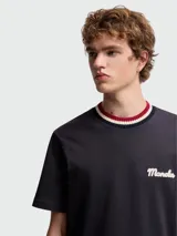 Camiseta de manga corta color blanco hueso con cuello redondo de punto acanalado a rayas en tonos rojo, azul marino y blanco. Presenta un pequeño logo bordado en azul marino en el pecho.