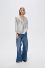 Camisa holgada de viscosa con estampado de rayas verticales en blanco y negro, cuello en V y mangas 3/4 con detalle de botones.