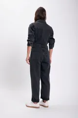 Mono de jean negro con cuello camisero, cierre frontal con botones y bolsillos en el pecho y laterales.