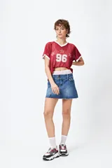 Minifalda de jean tiro bajo color negro con silueta evasé, dos tajos delanteros y ruedo desflecado.