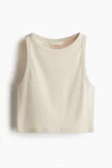 Musculosa cropped color crema en punto de algodón acanalado, con cuello redondo y ribete fino en escote y sisas.