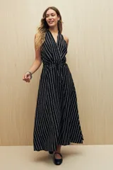 Vestido largo negro con estampado de líneas verticales blancas, escote halter y cintura con lazo.