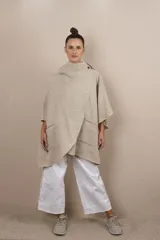 Ruana color beige confeccionada en lana fina sin teñir, con capucha, bolsillos y broche para usar cerrada. Terminaciones envivadas. Prenda oversize sin forro, cómoda, versátil y fácil de combinar.