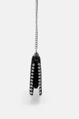 Bolso bandolera negro con tachas plateadas en los bordes. Tiene cierre de cremallera y asa de cadena extraíble.