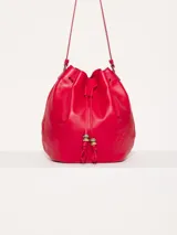 Cartera tipo bucket color rojo, de cuero, con cierre de cordón ajustable y correa larga para colgar del hombro.