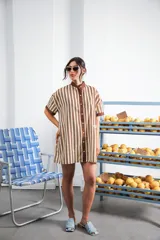 Vestido corto color crema con rayas verticales marrones, cuello mao, botones a tono y parche con logo en el frente.