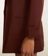 Blazer sastre femenino confeccionado en crepé color marrón, de modelo oversized y comprimento alargado. Sin estampa, posee bolsillos y detalle de pliegues en los puños.