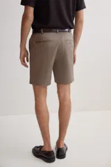 Short color marrón claro, de corte recto y largo a la rodilla. Presenta cintura con elástico en los laterales, cierre con botón, bolsillos al bies y bolsillos traseros ribeteados con botón.