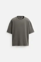 Camiseta color gris verdoso de punto tejido en hilatura de algodón, con cuello redondo, manga corta, efecto lavado y acabados irregulares.