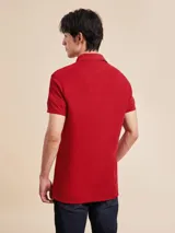 Chomba Tommy Hilfiger color rojo de corte slim, con cuello polo, cartera de dos botones, mangas cortas con ribete blanco y logo de la marca bordado en el pecho.