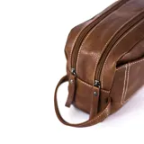 Neceser marrón oscuro de símil cuero con dos divisiones independientes con cierre superior individual y bolsillos internos. Tiene un bolsillo frontal con broche magnético, un bolsillo trasero con cierre y un asa lateral.