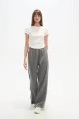 Pantalón deportivo negro de corte ancho y tiro alto, con cintura elástica y cordón ajustable. Presenta una raya blanca vertical a cada lado.