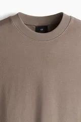 Remera color marrón topo de punto de algodón pesado, corte oversized, cuello redondo ribeteado, hombros caídos y bajo recto.