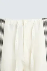 Pantalón de lino color crudo con rayas verticales negras, corte relaxed fit, cintura elástica ajustable con cordón, bolsillos laterales y traseros.