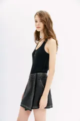 Minifalda negra cruzada de cuero ovino con apliques de tachas y piedras.
