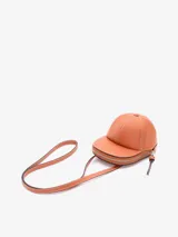 Bolso bandolera JW Anderson modelo Cap, con forma de gorra de béisbol, color marrón con costuras en contraste color crema y cierre superior con cremallera.