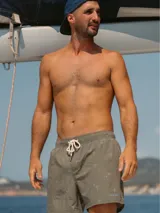 Short de baño blanco con estampado de hojas de palmera en tonos verde, rojo y amarillo.