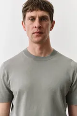 Remera verde claro de punto fino suave con remate acanalado en cuello, mangas y bajo. Corte ajustado que realza el contorno del cuerpo creando una silueta entallada.