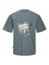 Remera azul con estampado de una mesa con sillas, una planta y luces colgantes.